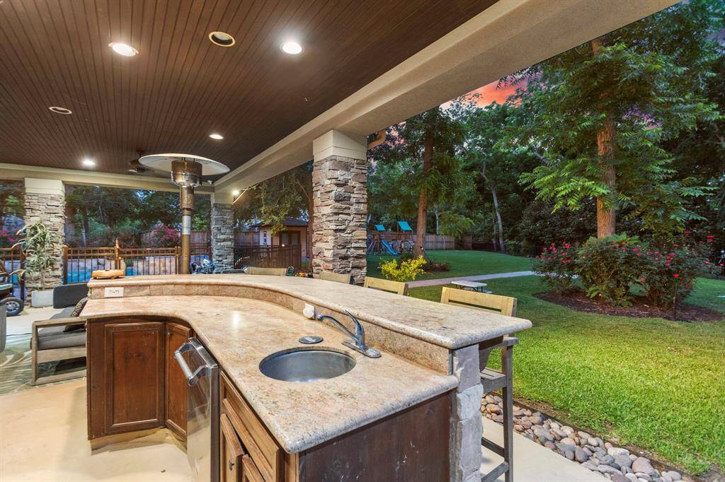 Outdoor kitchen and bar area with a stone countertop and sink.