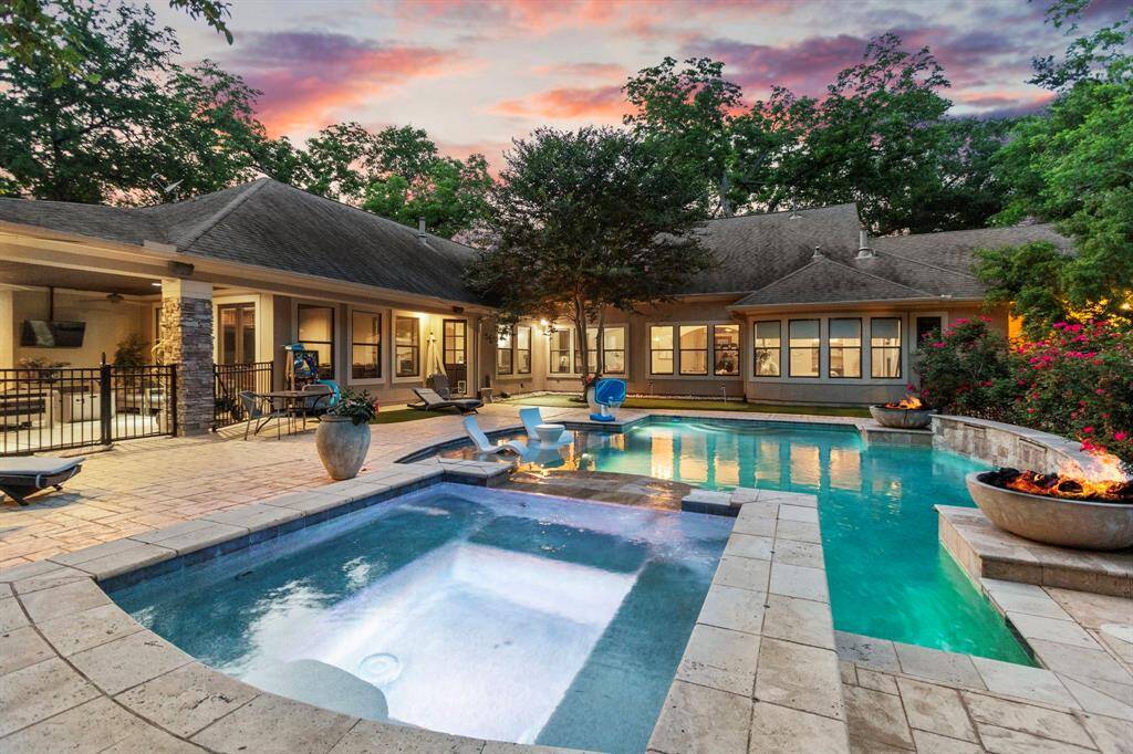 This stunning home features a spacious backyard with a luxurious pool, hot tub, and outdoor seating area.