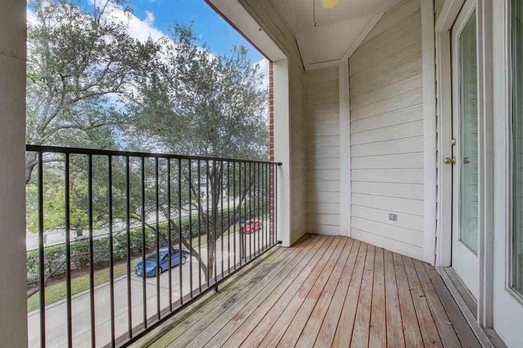 The flex space opens to the balcony, overlooking the private street, shaded by trees.