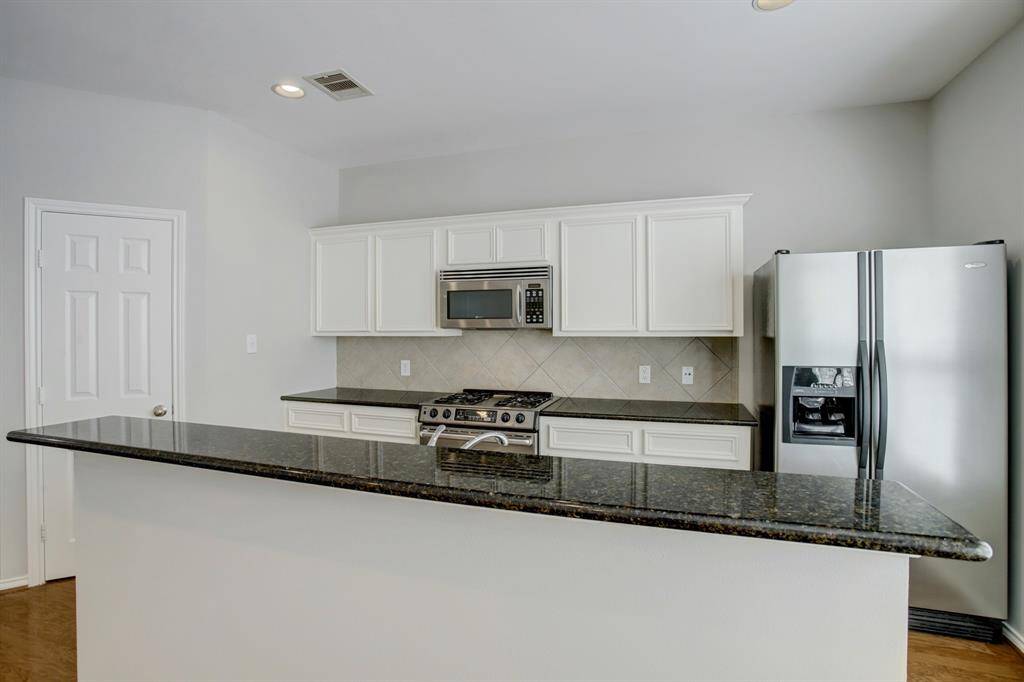 Breakfast bar with space for barstools. Stainless steel refrigerator with ice dispenser and water filter.