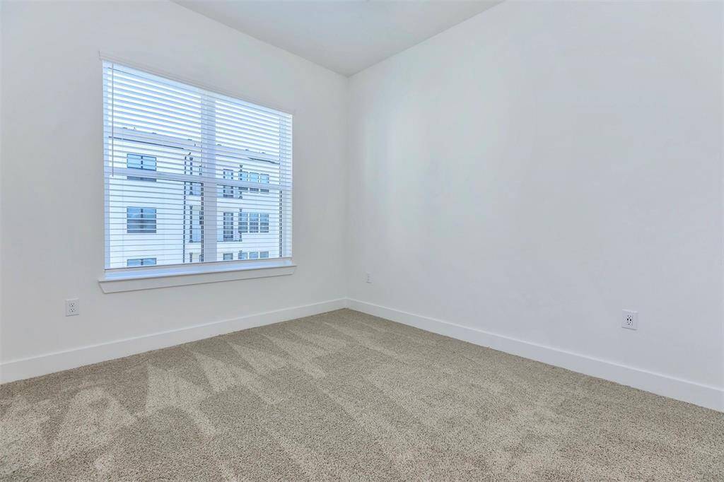 Second bedroom with walk-in closet, large window, and natural light
