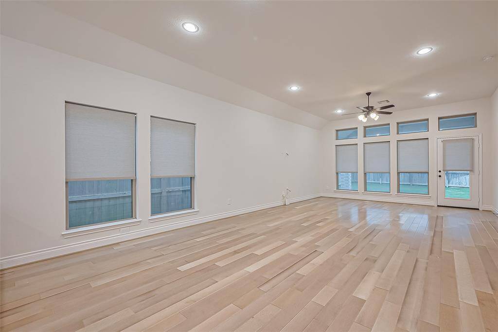The adjoining dining area and family room are bathed in natural light from a wall of windows, providing stunning views of the backyard and easy access to the extended covered patio. Custom shades throughout the home ensure both comfort and privacy at any hour of the day.