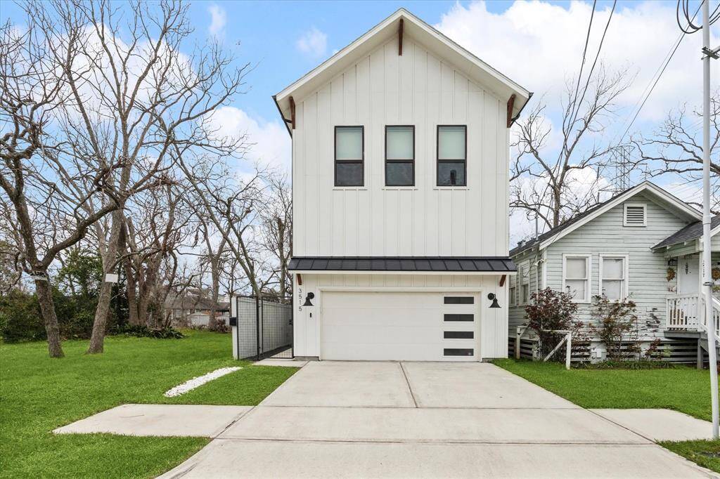 Batten board siding exterior, modern farmhouse style with modern garage door. Double wide driveway and gated side entry.