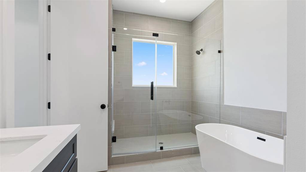 The primary bathroom features a walk-in shower with tile surround and separate soaking tub.