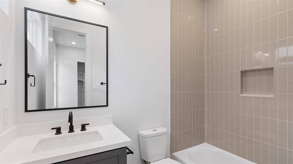 Secondary bathroom features atub/shower combo with tile surround.