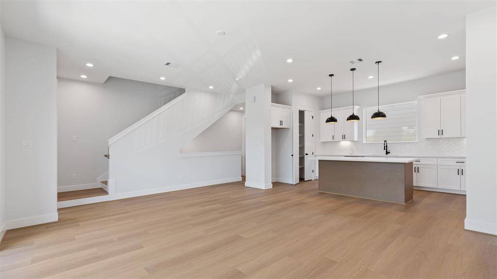 Living room features beautiful flooring, recessed lighting, high ceilings, and a wallof windows.
