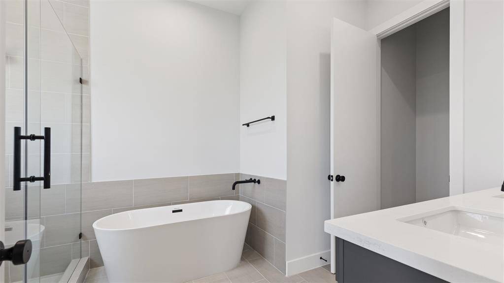 The primary bathroom features a walk-in shower with tile surround and separate soaking tub.