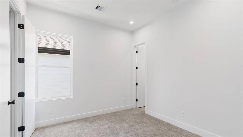 Secondary bedroom features awindow and plush carpet.