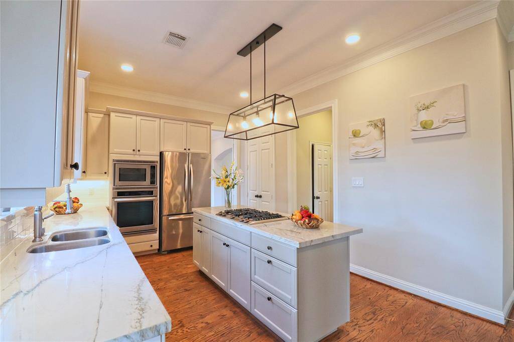 Modern kitchen featuring sleek gray cabinets, stainless steel appliances, included refrigerator, and stunning quartz countertops.