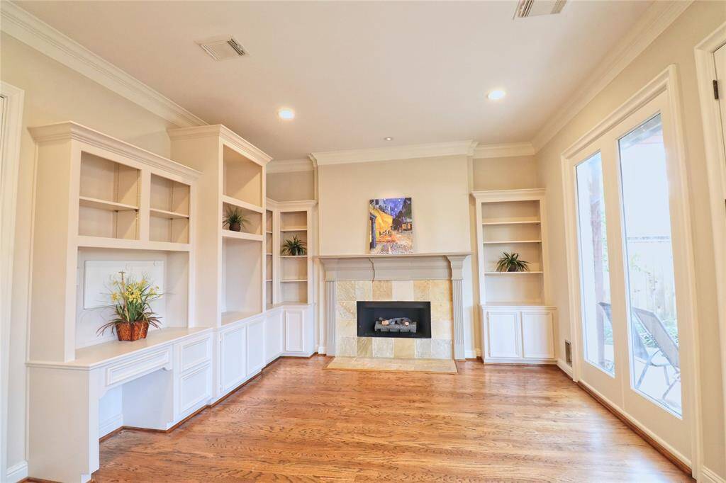 Elegant breakfast room/den featuring built-in bookcases, a cozy gas fireplace, and double French doors leading to the backyard.