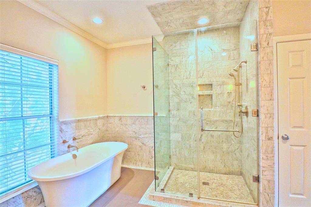 This primary bathroom features a luxurious freestanding bathtub beside a large window, The space is bright and modern, offering a spa-like retreat.
