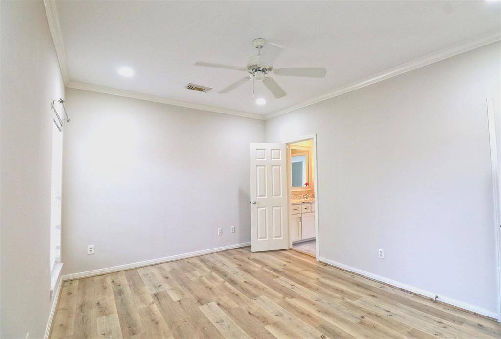 Bright secondary bedroom with new laminate flooring, a ceiling fan, and fresh paint.