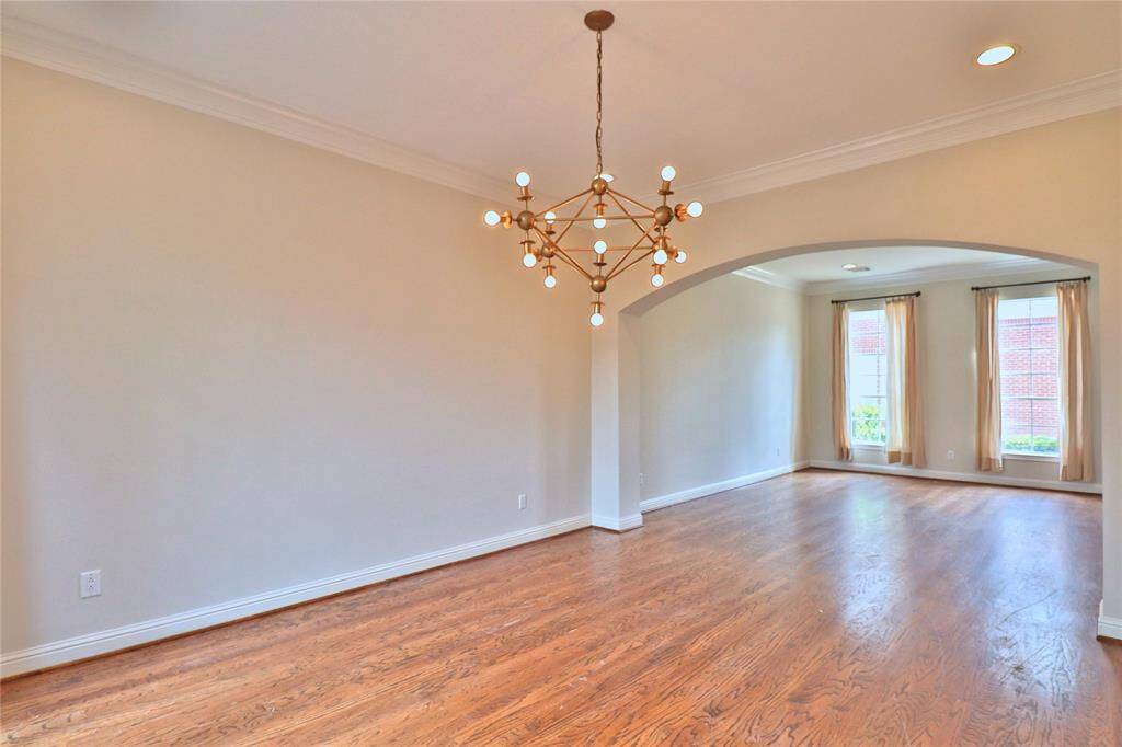 The dinning room features hardwood floors and a modern chandelier