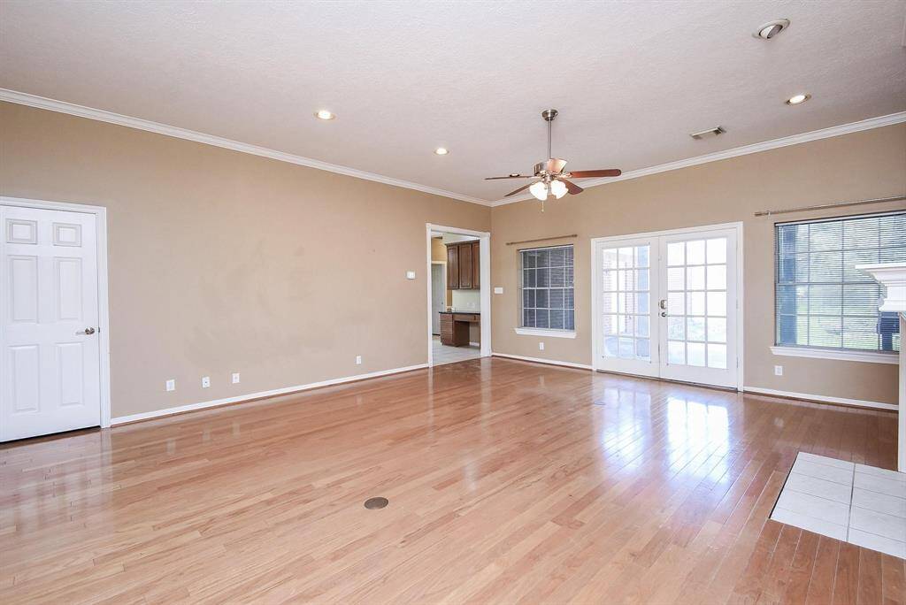 This large living area features views of the lovely, tree-filled backyard, a natural wood floor, and plenty of room for seating and entertaining.