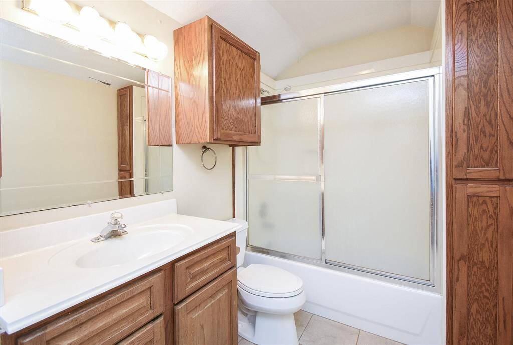 A well-appointed bathroom featuring a large vanity, warm wood cabinetry, and a combination shower/tub for convenience and comfort.