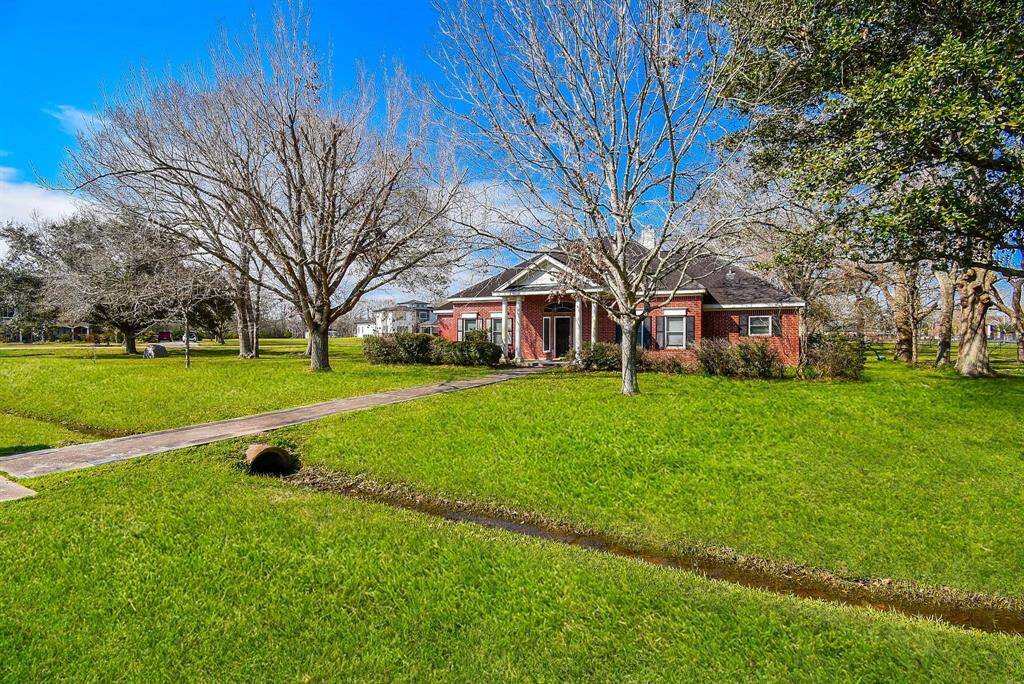 Nestled among mature trees, this elegant single-story brick home offers a peaceful setting with lush landscaping and a spacious front yard