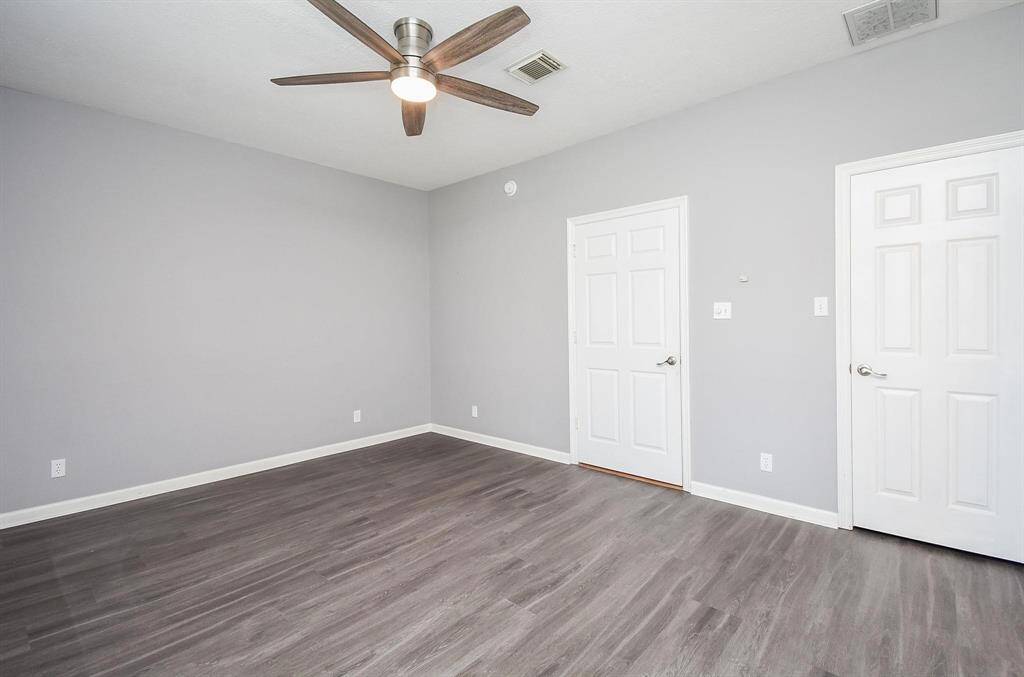 A well-lit bedroom with neutral tones, a ceiling fan, and ample space, ready to be customized to fit any style.