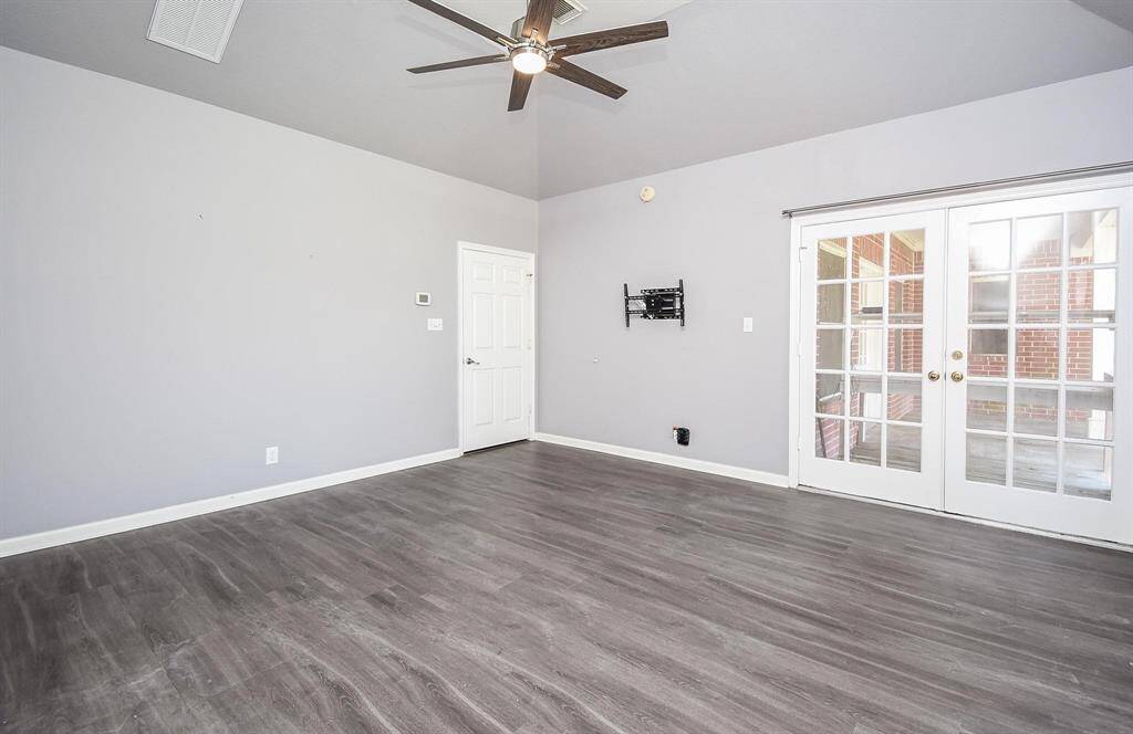 A large bedroom with a ceiling fan, stylish flooring, and abundant natural light, creating a cozy and welcoming atmosphere