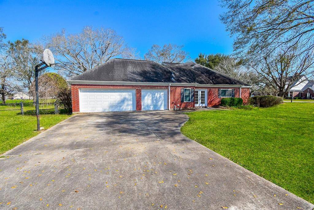 A spacious driveway leading to a two/three-car garage, framed by a beautifully landscaped front yard