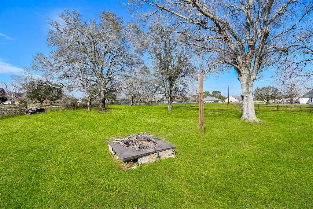 A serene backyard with mature trees, a firepit area, and plenty of open green space for outdoor enjoyment