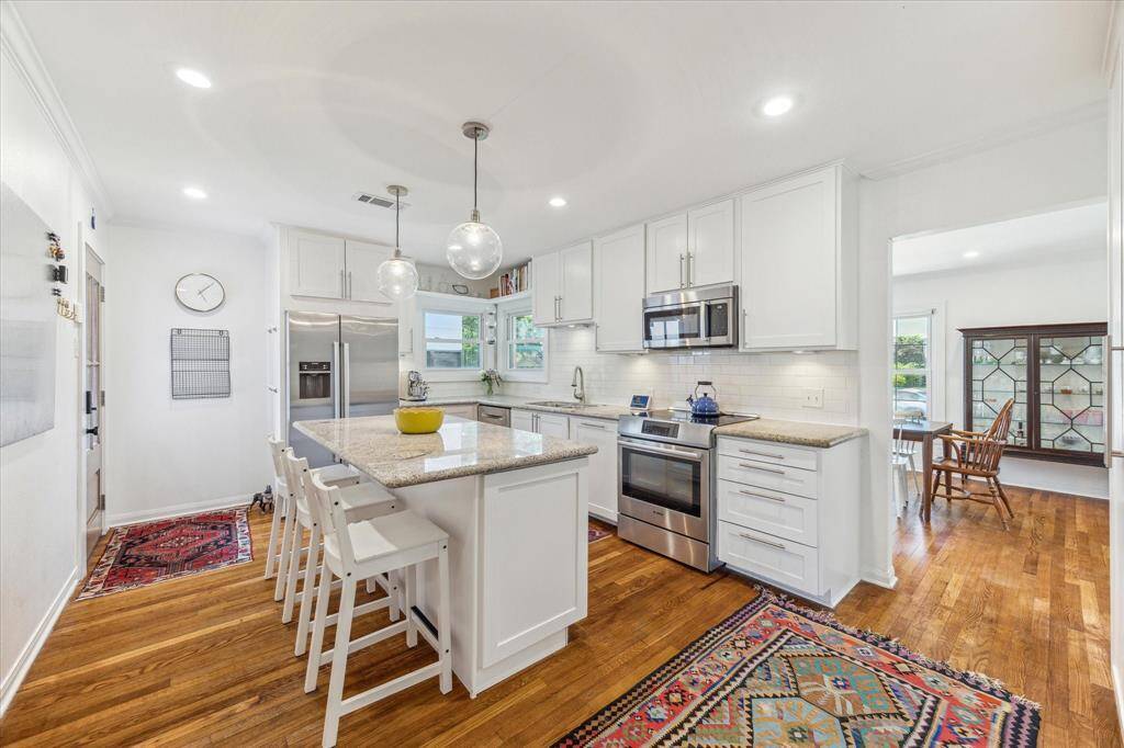 Light and bright kitchen with stainless appliances and island seating for three. Side door opens to the gated driveway.