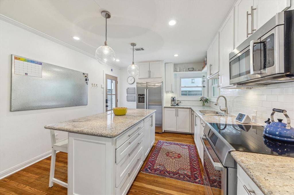 The kitchen includes storage within the island and pendant lighting.