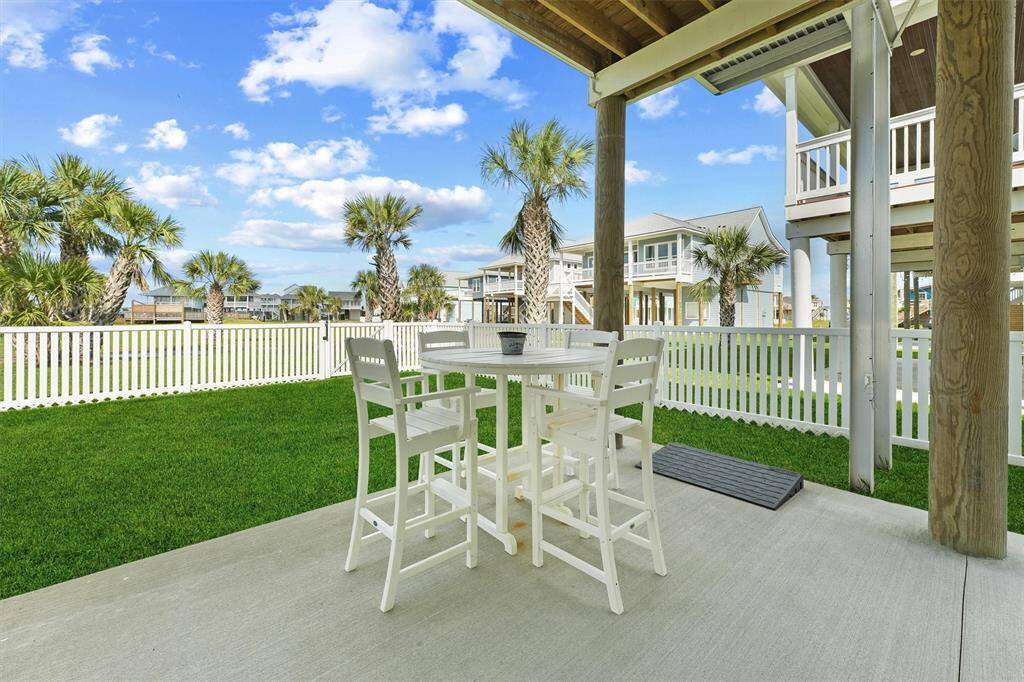 Enjoy al fresco meals under the covered patio with this inviting outdoor dining setup, surrounded by lush lawn and charming coastal scenery
