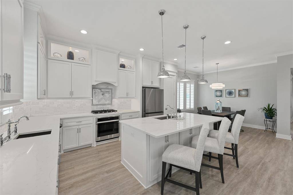 This stunning culinary space features custom cabinetry, quartz countertops, a statement marble backsplash, and premium stainless appliances