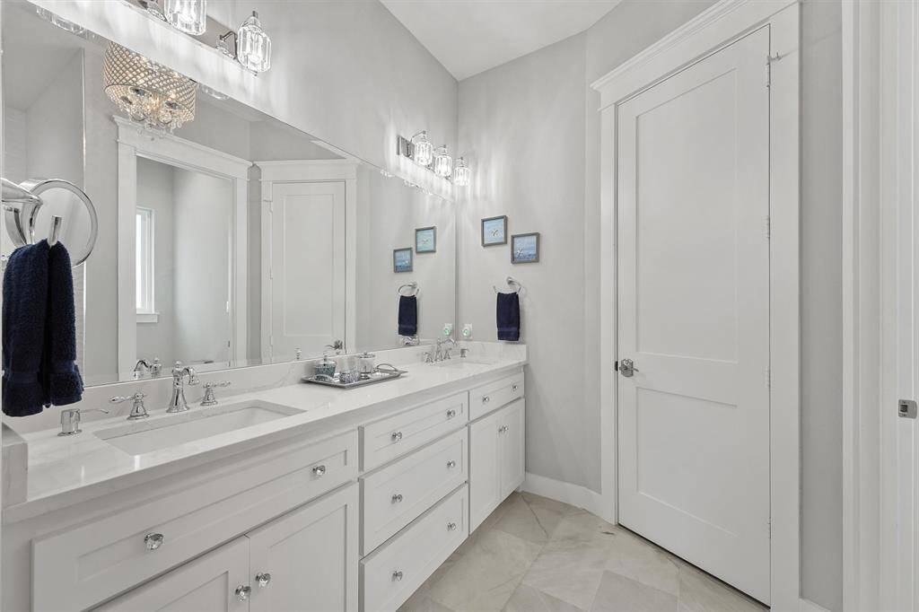 The primary bath features an expansive dual-sink vanity with abundant storage, sleek hardware, and elegant lighting