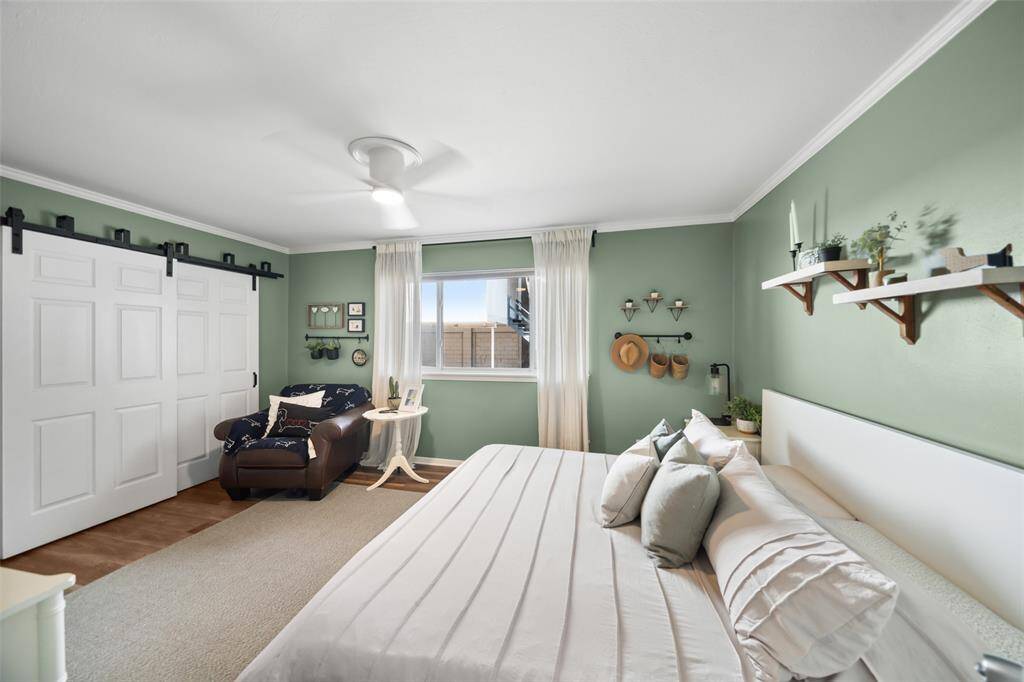 This cozy bedroom features calming green walls, a large window for natural light, and stylish barn doors over the closets. Large enough for a king-size bed, plus a sitting area.