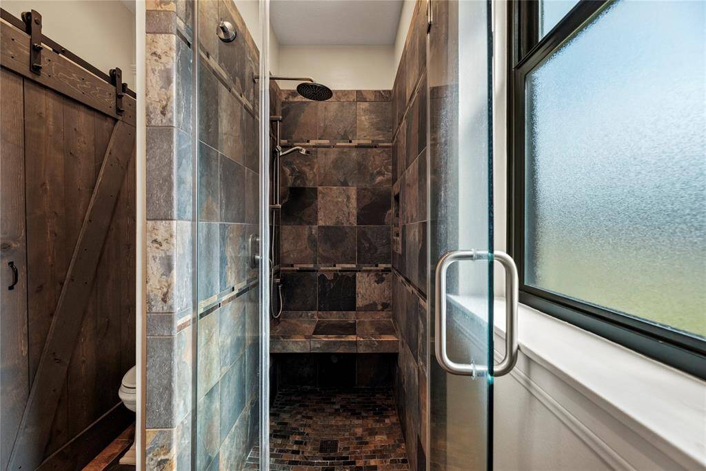 Matching tile work in the shower provides consistency in design. Early mornings are made brighter and warmer in the spacious shower featuring built-in shelf for self-care items and bench!