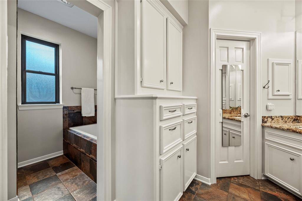 The primary bathroom boasts ample storage featuring spacious built-in cabinets.