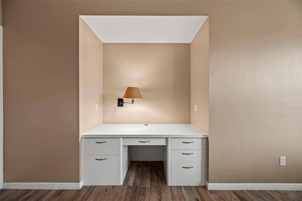 Built-in desk nook featuring ample drawer storage. The space is accented by a wall-mounted light fixture and offering a cozy and functional workspace.
