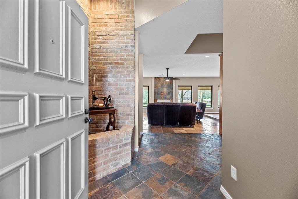 Entering the home, guests are met with durable tile flooring, which is accented with white baseboards and an attractive wood front door