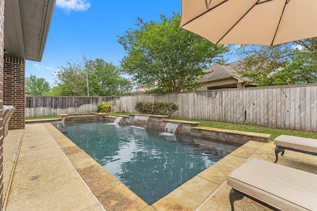 Step out into your charming backyard oasis, featuring a tranquil waterfall pool and spa.