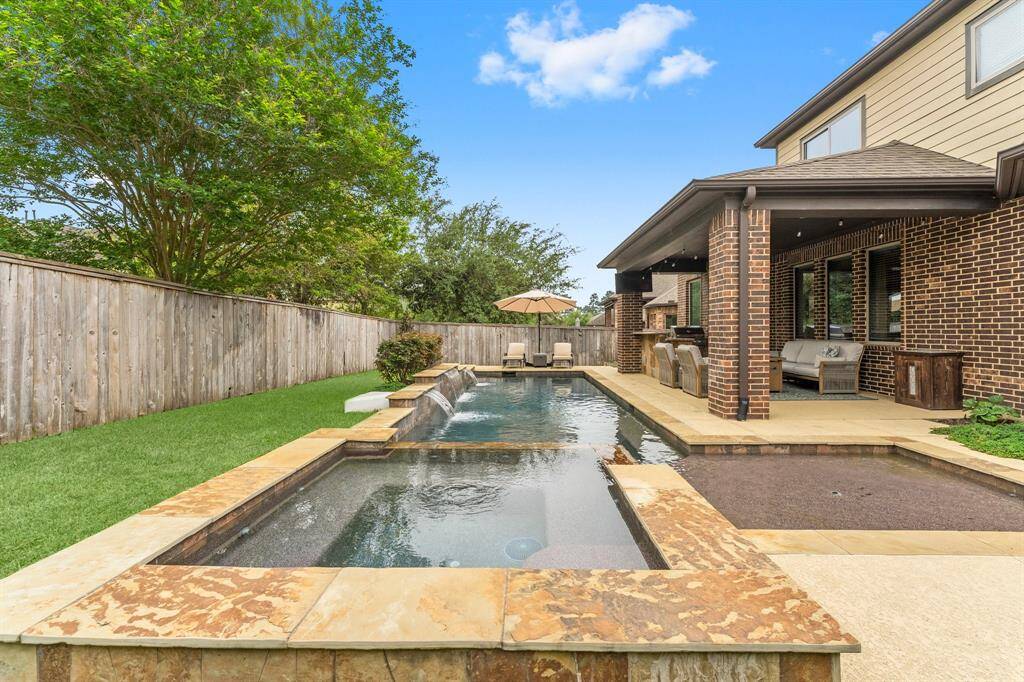 The spacious spa offers ample in-pool seating along with raised seating around the edge, creating the perfect spot to relax. Just off to the side, a tanning ledge with space for an umbrella provides a cool retreat for those extra hot days when you want to lounge in the water.