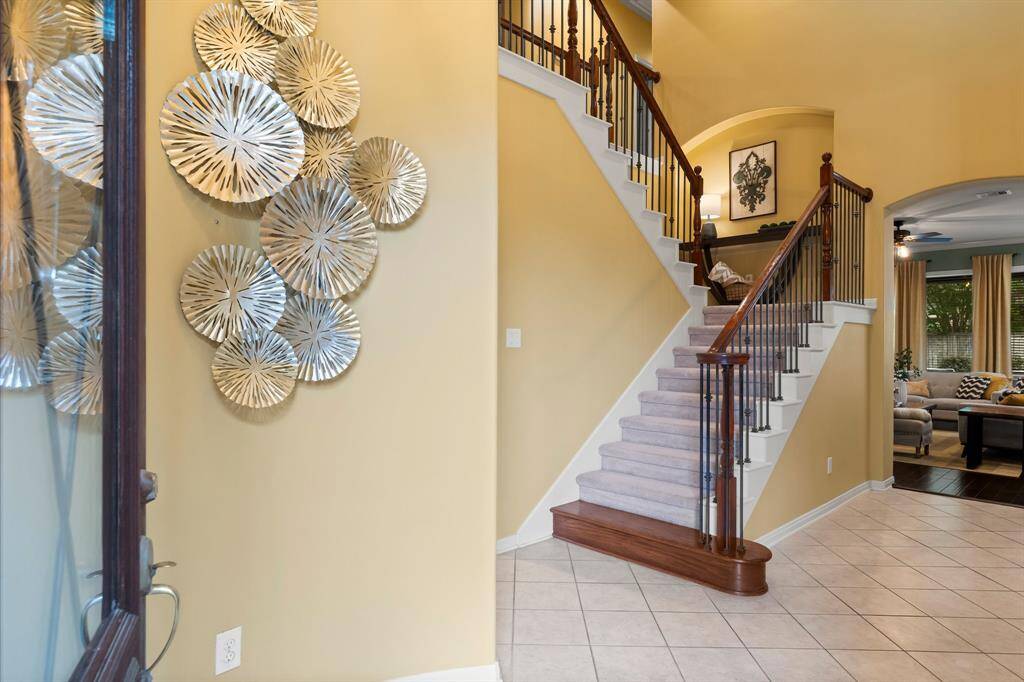 This inviting entryway features a stylish staircase with wooden railings leading to a cozy living area.
