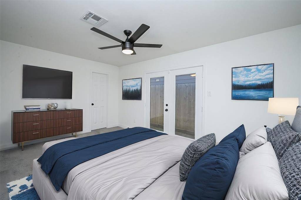 Virtually Staged: Secondary bedroom with a ceiling fan, a built-in closet, and double glass doors with access to the side yard.