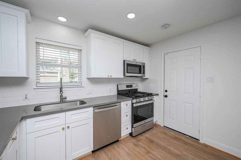 The kitchen features stainless steel appliances, recessed lighting, quartz countertops, and plenty of wooden cabinetry.