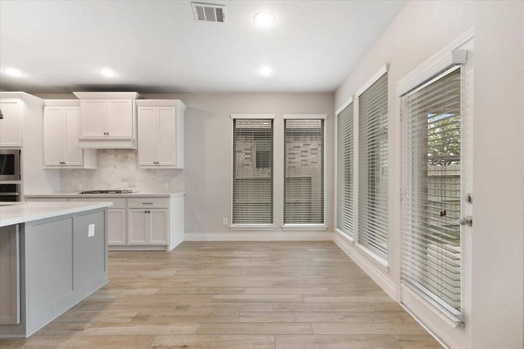 Bright, modern kitchen with sleek cabinetry, stainless steel appliances, and large windows providing ample natural light. The open layout and neutral tones create a welcoming space.