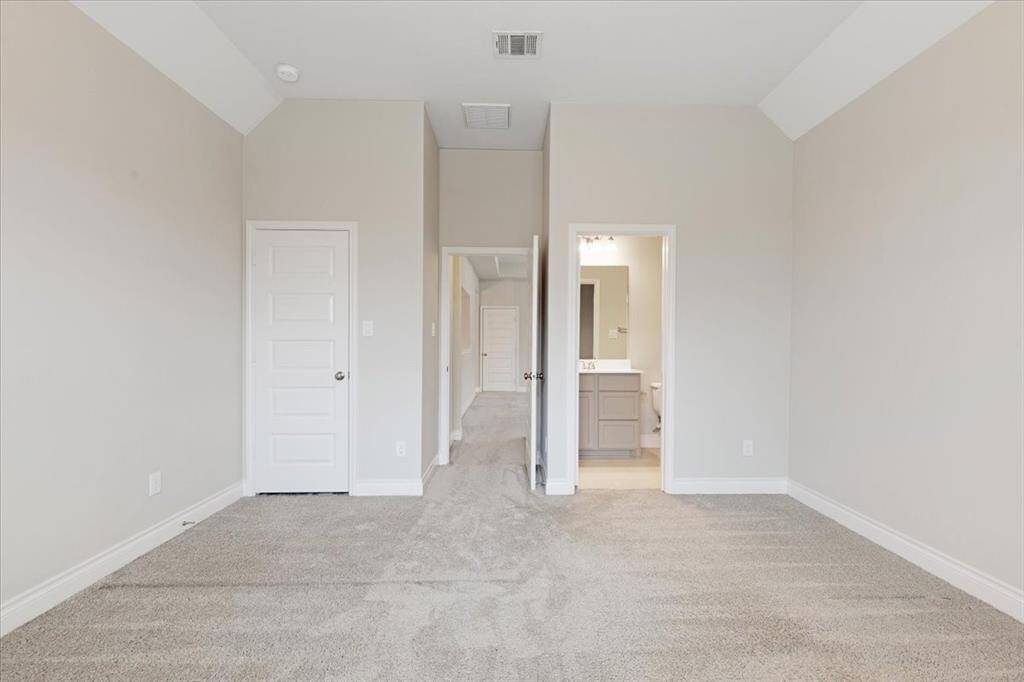 This room features a neutral color palette with plush carpeting, a high ceiling, and a modern design. It includes a closet and an ensuite bathroom, highlighting functionality and comfort.