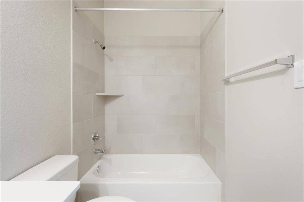 This is a clean, modern bathroom with a tiled shower and bathtub combo, featuring neutral tones and minimalist fixtures.