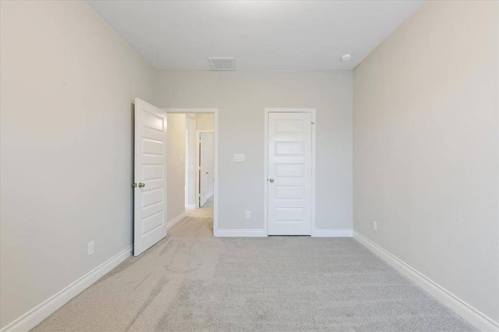 Bright, cozy room with neutral tones and two white doors, perfect for a bedroom or home office.
