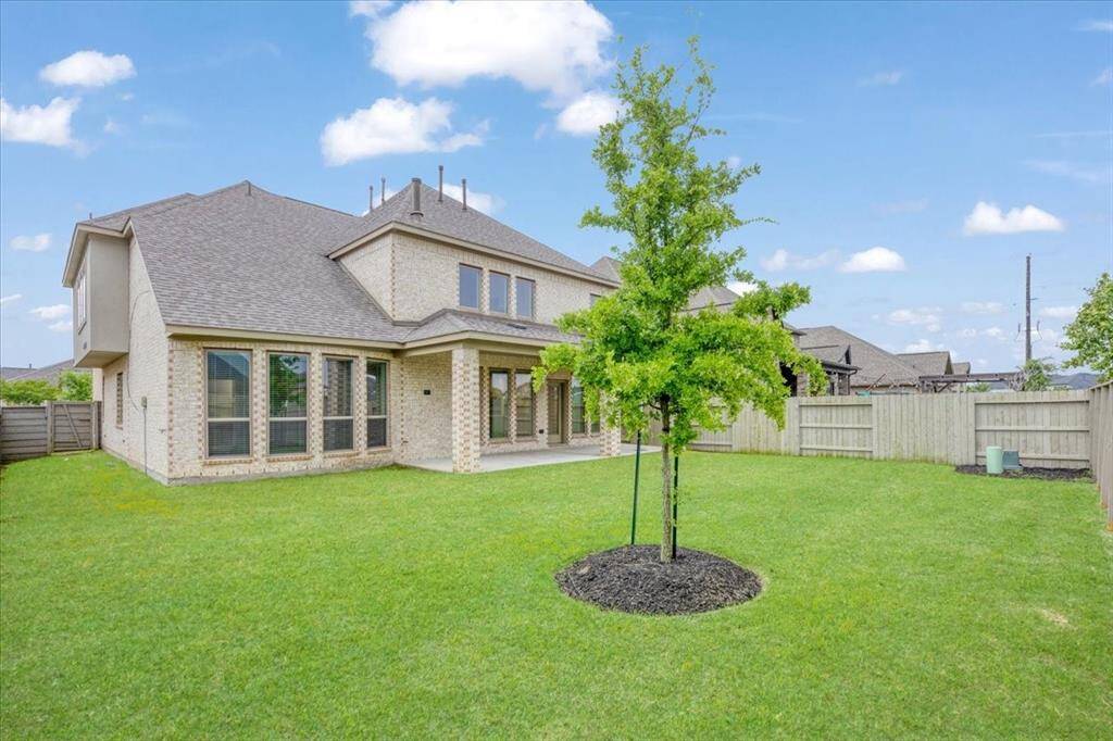 This is a spacious two-story brick home with a well-maintained lawn, featuring a covered patio and a fenced backyard, ideal for privacy and outdoor activities.