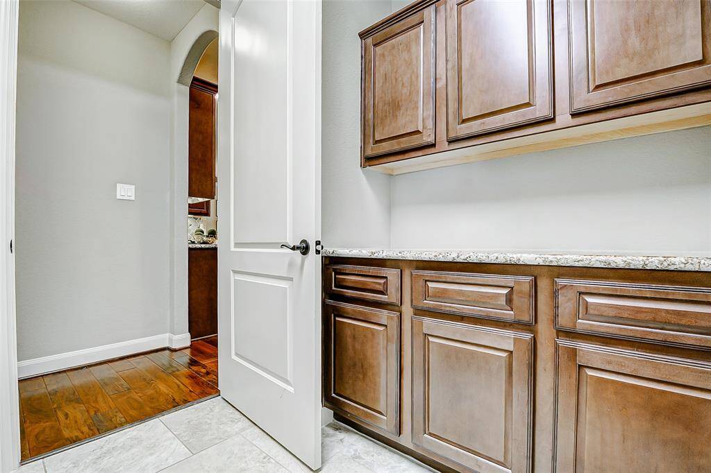 Additionally, across from the washer and dryer, there is a built-in set of cabinets with granite countertops offering an ideal surface for folding laundry and extra storage space.