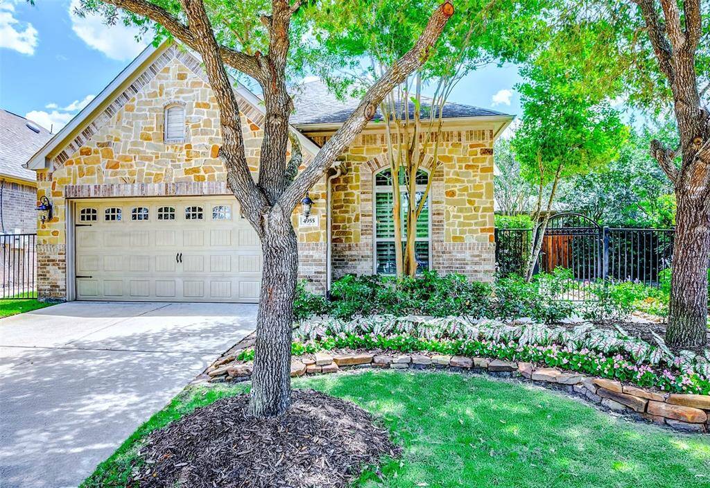 This well manicured yard offers flower beds bordered by natural stone and features mature decorative foliage.