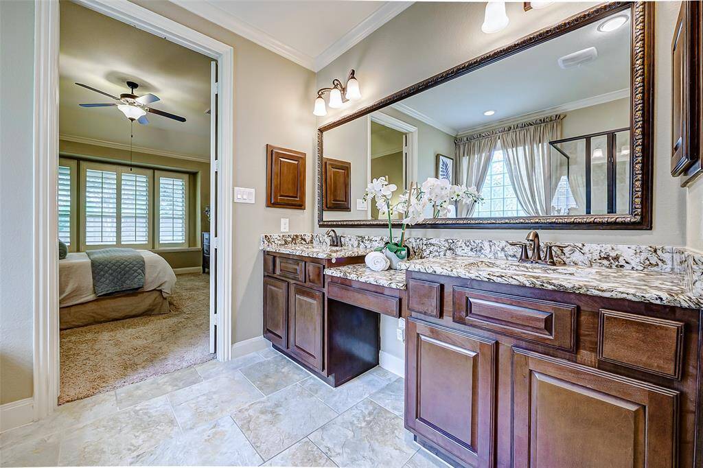 A large framed mirror and overhead lighting brighten the space, creating an open, inviting atmosphere. Dual medicine cabinets offer additional storage, keeping the countertop clutter-free.