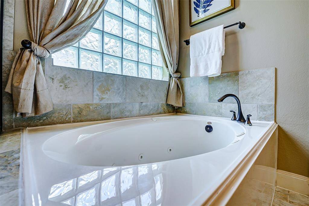 A nearby jetted tub is thoughtfully placed beneath a large glass block window.
