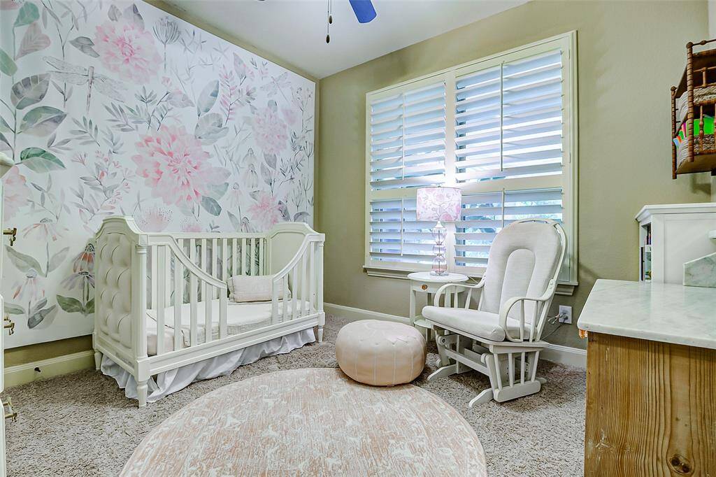This secondary bedroom offers an inviting space, highlighted by a large window fitted with plantation shutters that enhance both style and privacy.