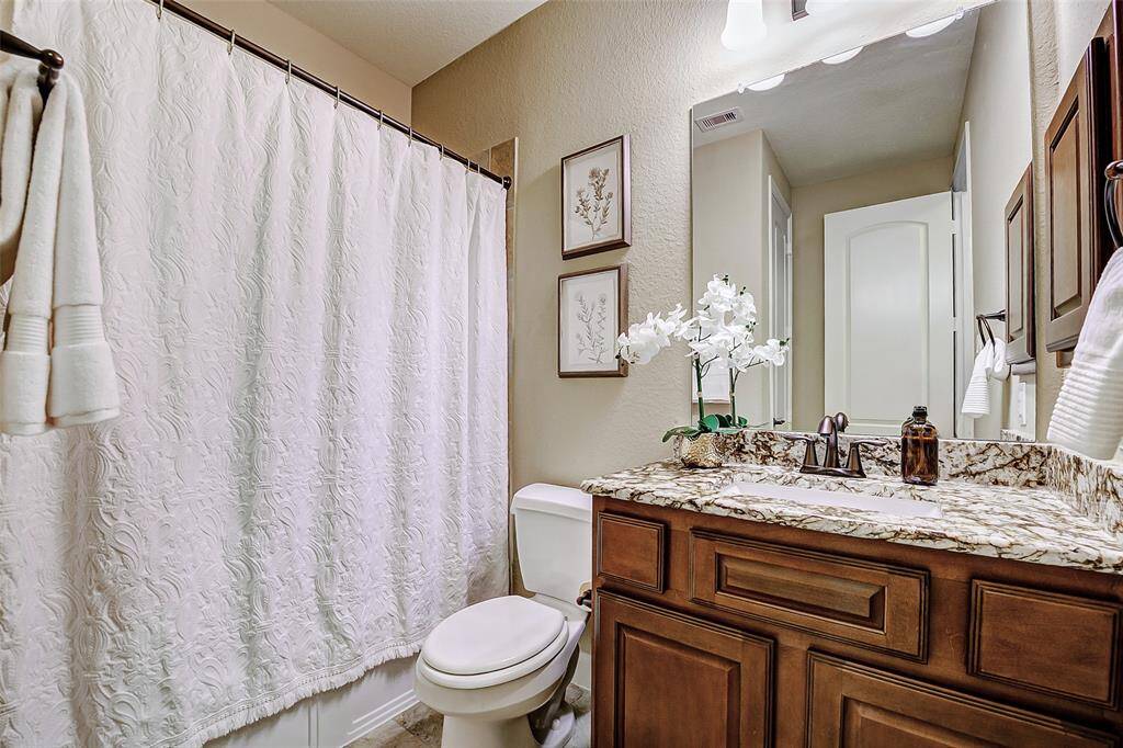 This well-appointed secondary bathroom showcases a stylish granite-topped vanity and a full size linen closet. The tub-shower combo offers versatile bathing options, allowing you to enjoy a relaxing soak or a quick shower, making this space both functional and adaptable to your needs.